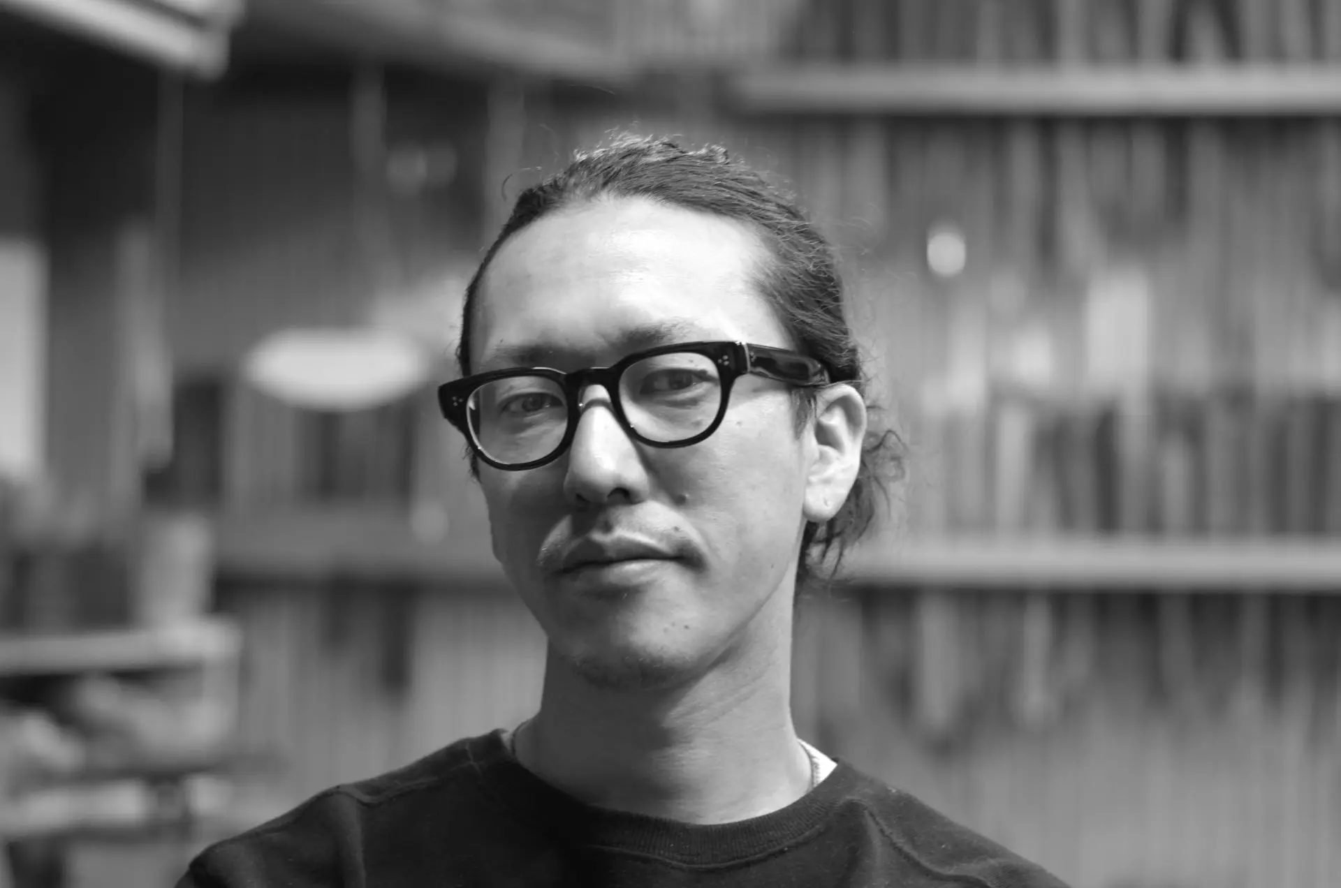 眼鏡をかけた錫師・志村泰利のモノクロの肖像